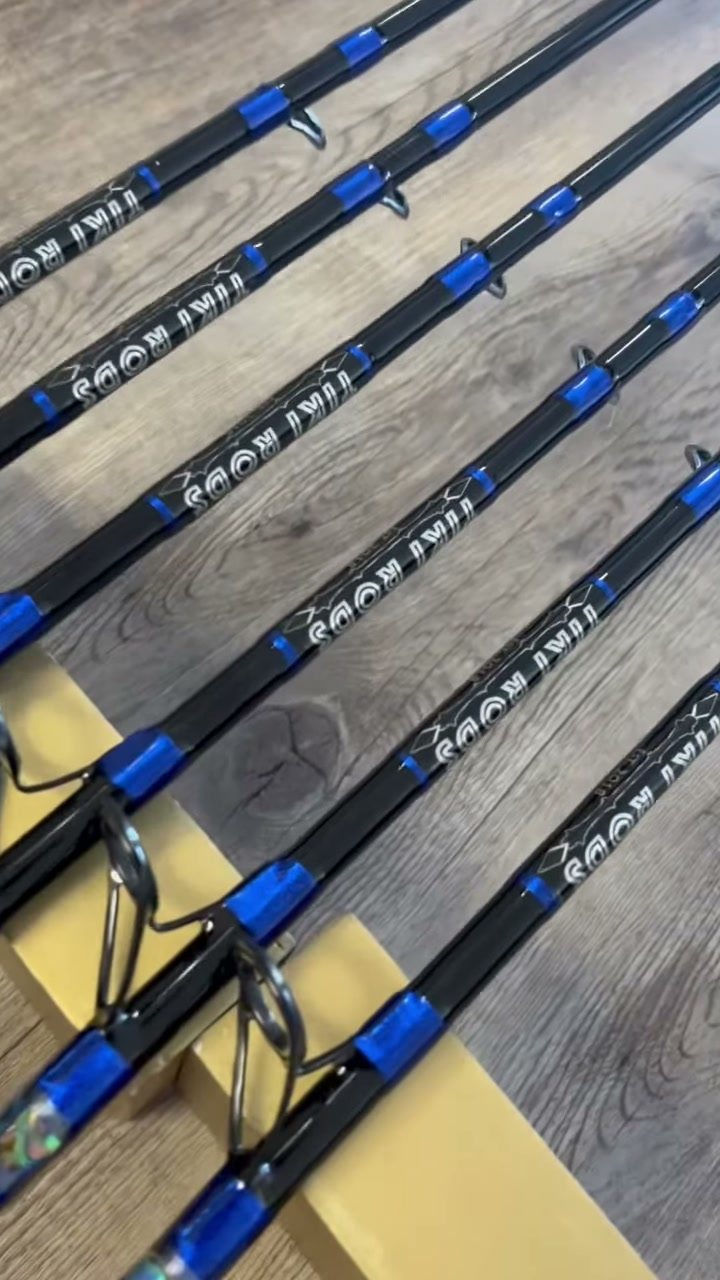 Blue-wrapped custom rods laid out on the shop floor, each carrying the Tiki Rods decal