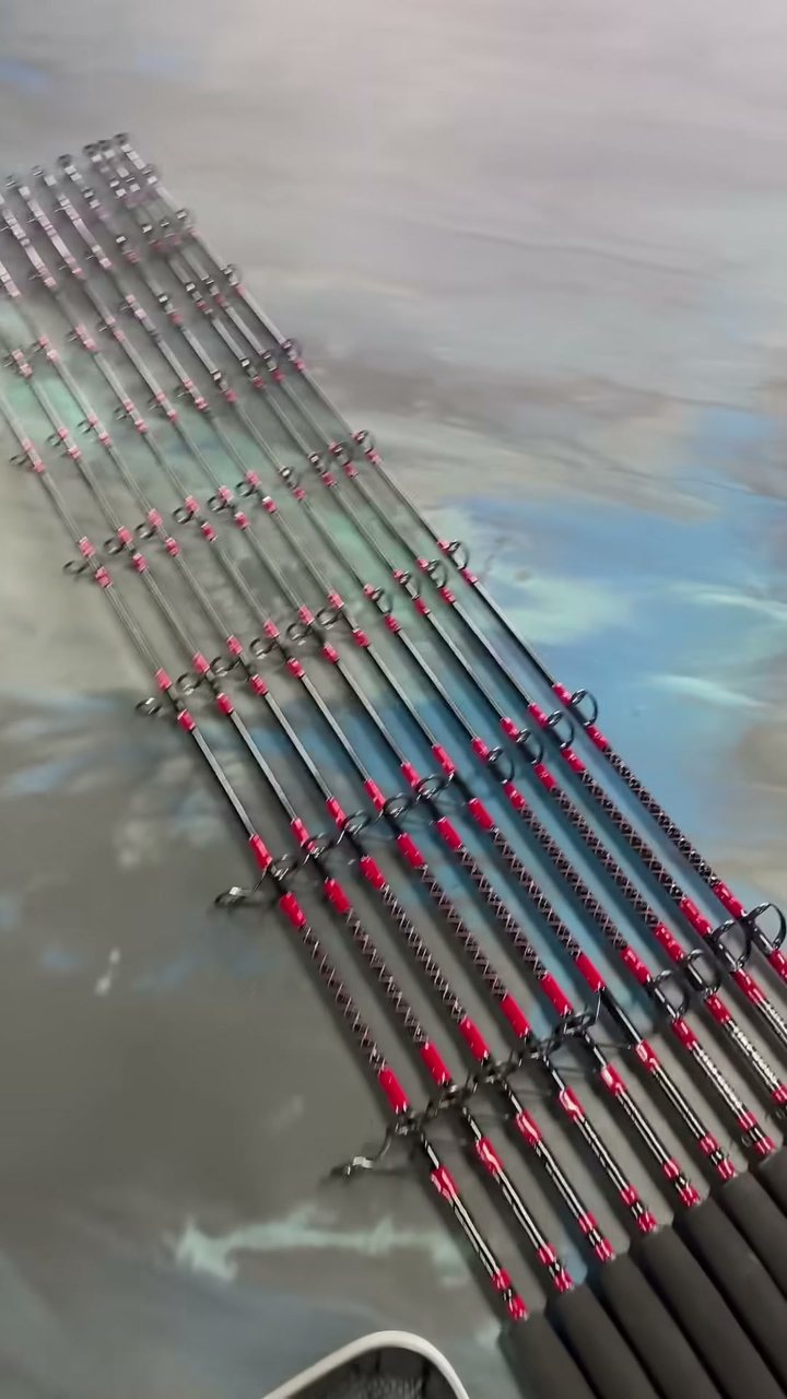 A matched set of tarpon rods fanned out, every guide wrapped in red thread