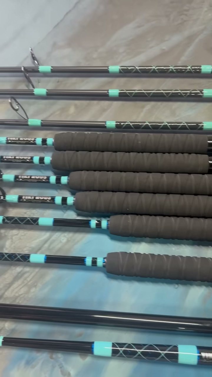 A finished set of custom rods on the bench, wrapped in seafoam teal thread over black blanks with EVA foam grips
