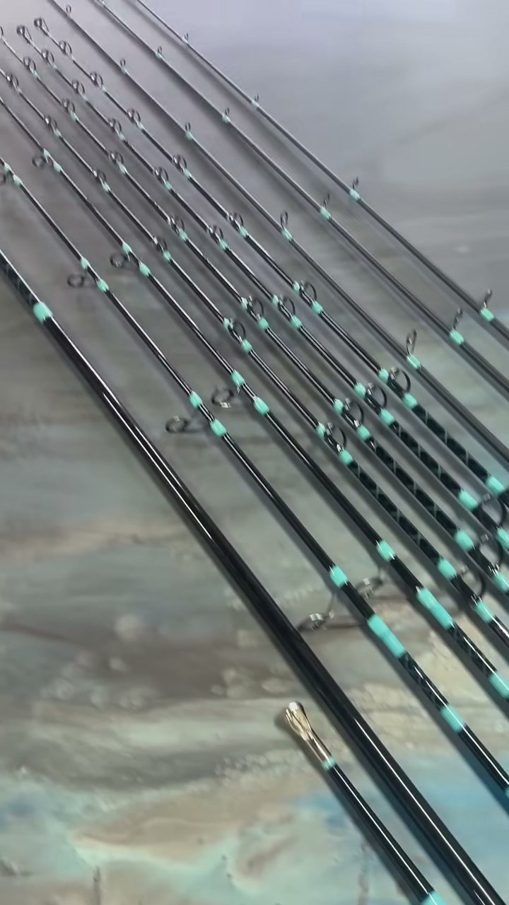 Long custom rods fanned across a marbled bench, each guide wrapped in matching teal thread